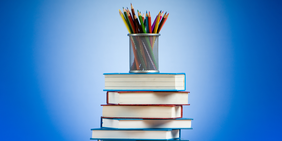 Buntstifte und Bücherstapel auf blauem Hintergrund